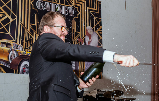 Mike Smith smashing open a bottle of champagne